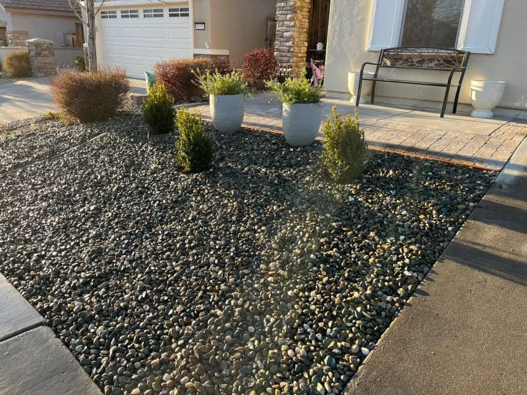 Landscape design featuring decorative gravel, potted plants, and a stone path.