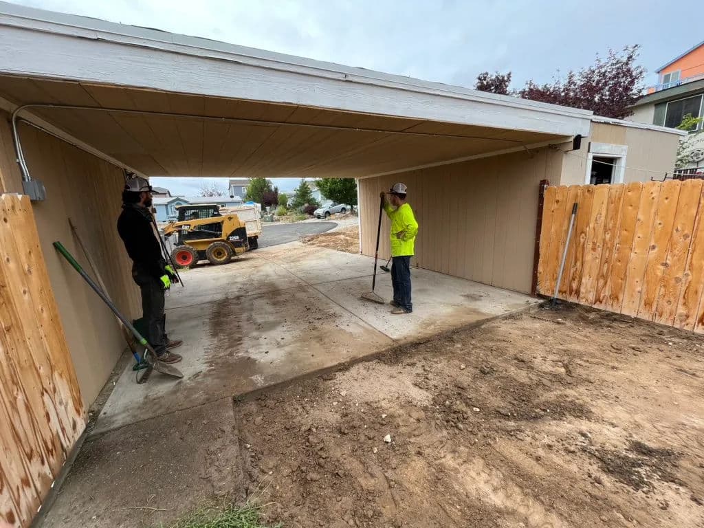 Workers preparing a garage space, with construction machinery and equipment on site.