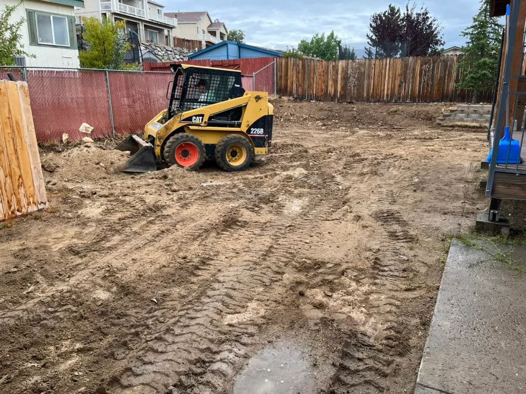 Caterpillar skid steer loader on a cleared construction site with dirt and tire tracks.