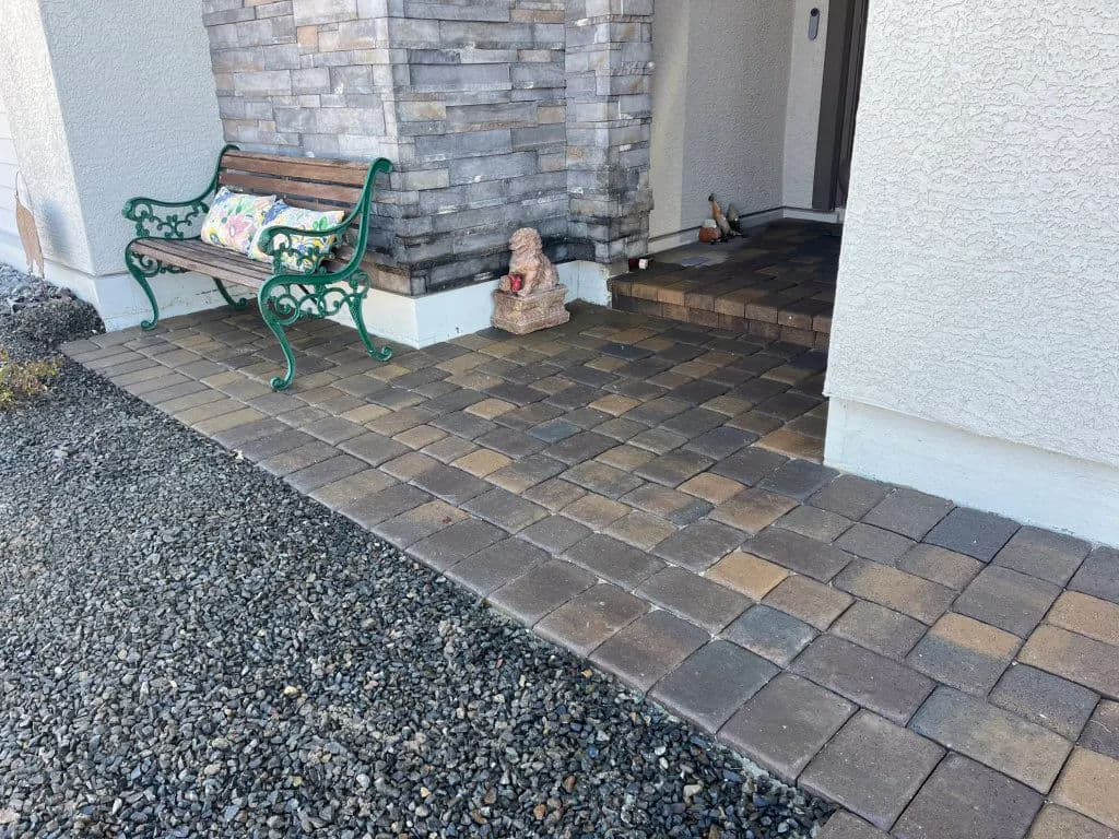 Entrance with stone pavers, a green bench, and decorative elements for a welcoming outdoor space.